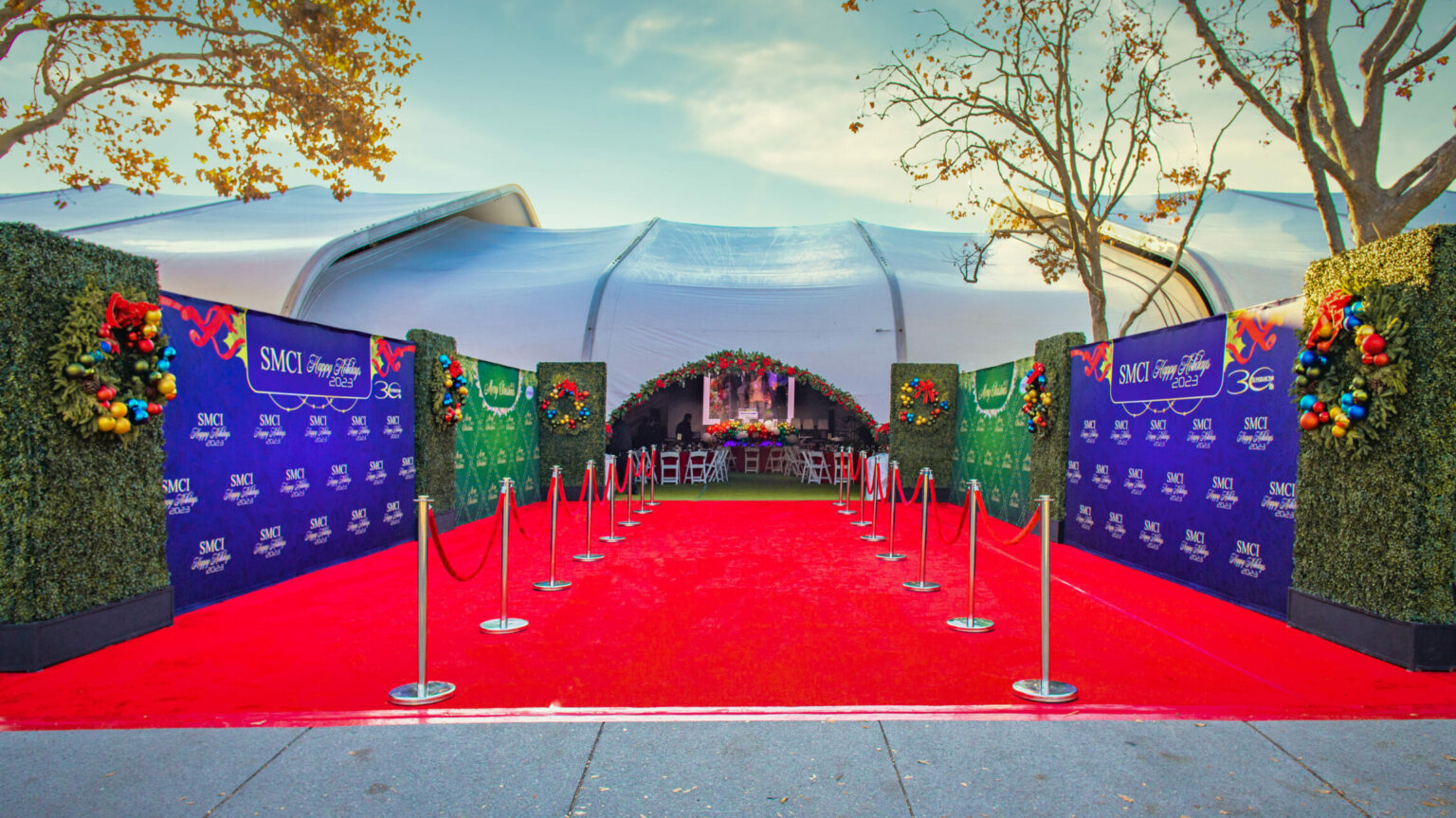 A vibrant picture of the Supermicro Entrance with red carpet, backdrops, hedges, and holiday wreathes